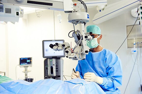 A doctor performs eye surgery on a patient