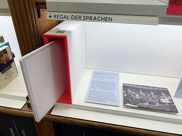 Barrierefreies_Parlament_c_Hilfsgemeinschaft_Regale_Braillebeschriftung.jpg Bücherregal mit Braillebeschriftung und herausziehbarem braillebeschrifteten Board in A4
