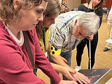 Mehrere Personen erstasten etwas bei einer Tafel