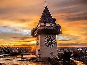 Foto: Graz Tourismus/Markus Spenger Grazer Uhrturm mit dem spitzen Dach im Sonnenuntergang.