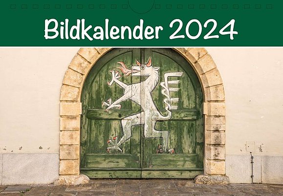 Cover Bildkalender 2024: grünes Holztor bemalt mit weißem Tier, das aussieht wie ein Pferd mit roten Krallen, Hörnern und Feuer speiend. Überschrift in weiß auf grünem Hintergrund: Bildkalender 2024