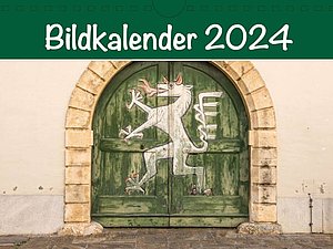 Cover Bildkalender 2024: grünes Holztor bemalt mit weißem Tier, das aussieht wie ein Pferd mit roten Krallen, Hörnern und Feuer speiend. Überschrift in weiß auf grünem Hintergrund: Bildkalender 2024